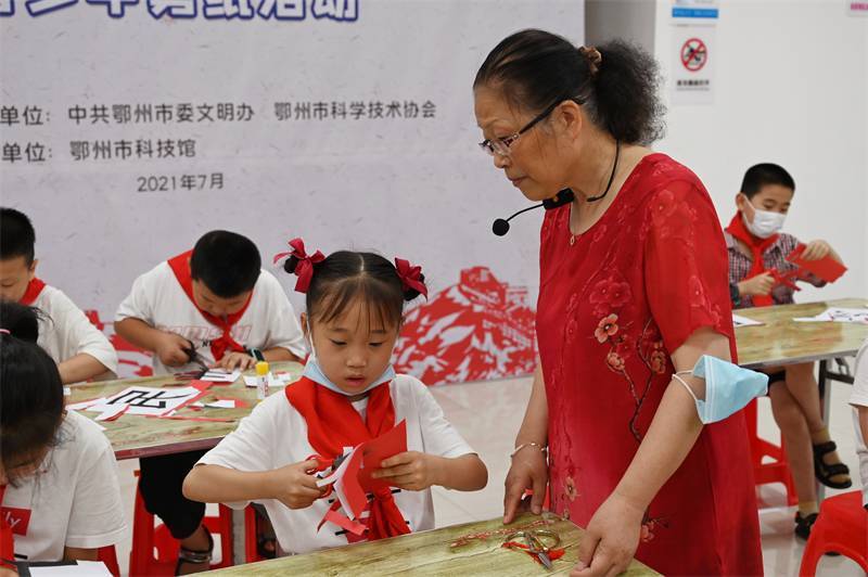 2021年7月10日，鄂州市科協(xié)組織落駕坪小學(xué)學(xué)生在鄂州市科技館開展社會(huì)主義核心價(jià)值觀系列活動(dòng)，圖為開展的紅色剪影圓夢(mèng)中華剪紙活動(dòng)，老師指導(dǎo)同學(xué)剪紙.jpg